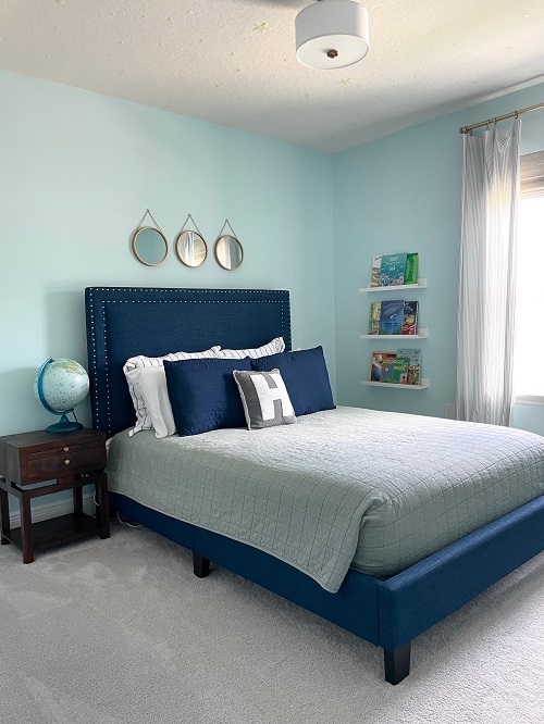 Navy bed in boys room with brown nightstand and globe