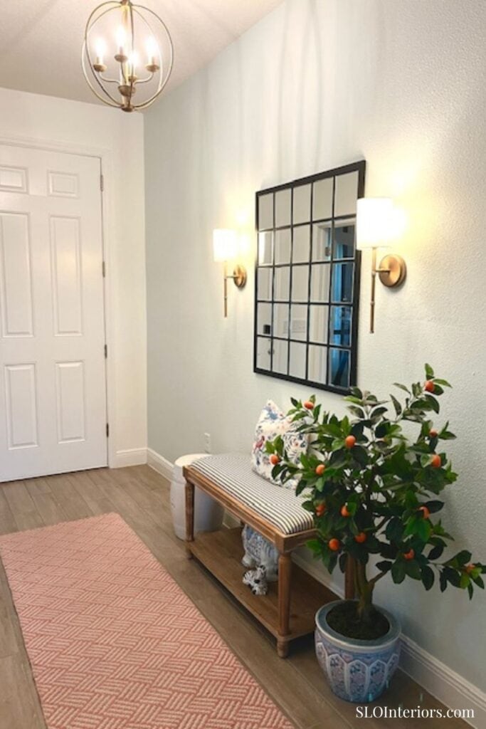 Entryway with gold chandelier and coral rug