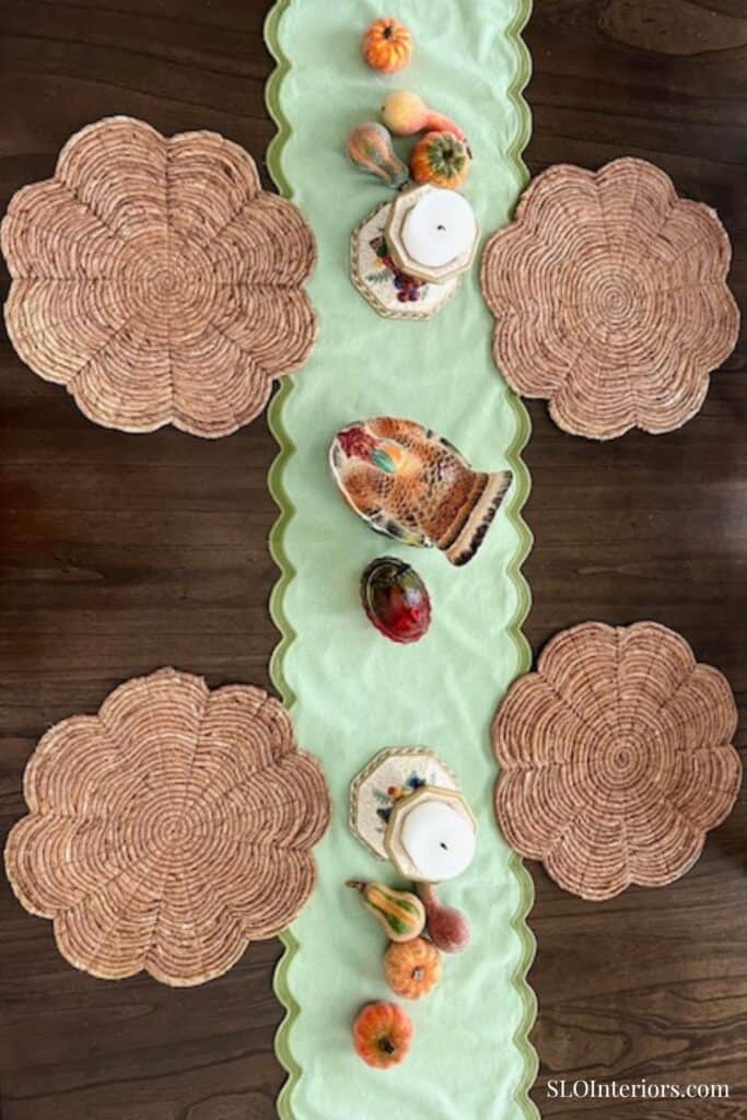 Overhead picture of ceramic turkey and candle holders on green table runner