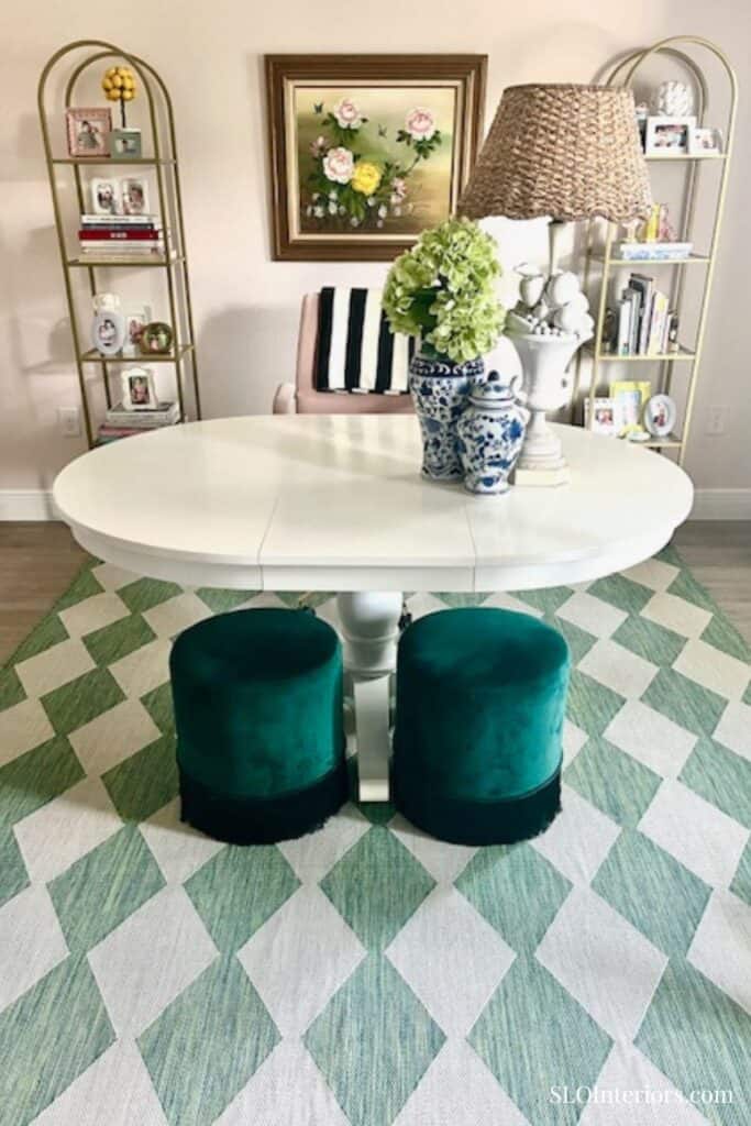 Light pink home office with white table and green stools