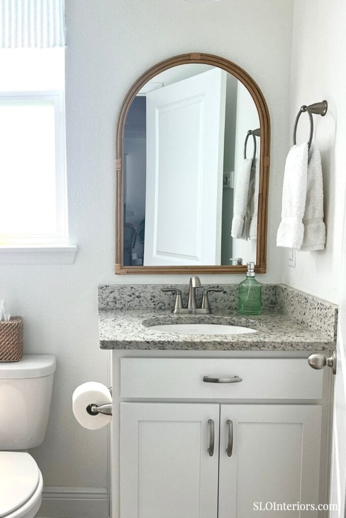 White half bath with arched wood trimmed mirror