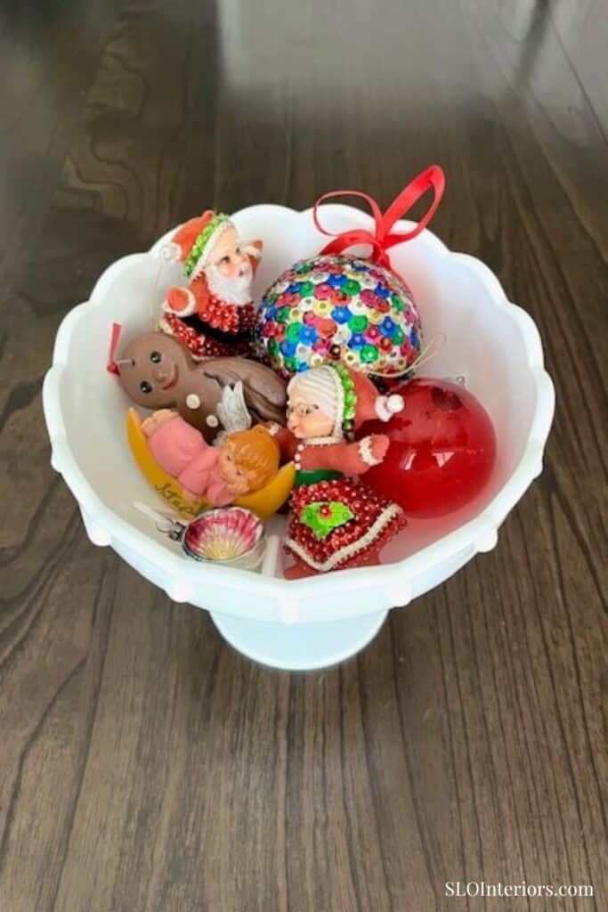 White vintage bowl full of Christmas ornaments
