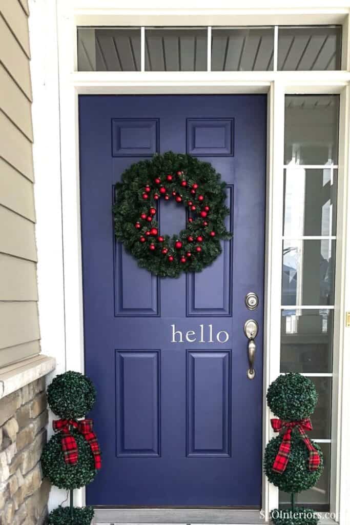Festive navy blue front door decorated with holiday wreath and ornaments.