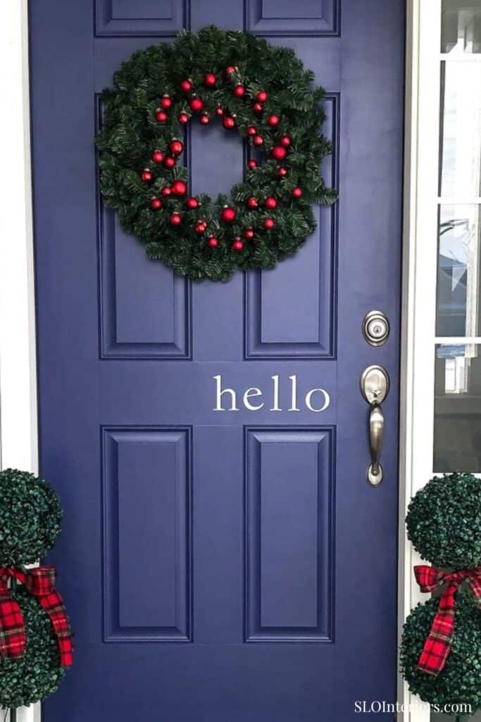 Christmas wreath with red ornaments on a blue front door, holiday decor, welcoming entrance.