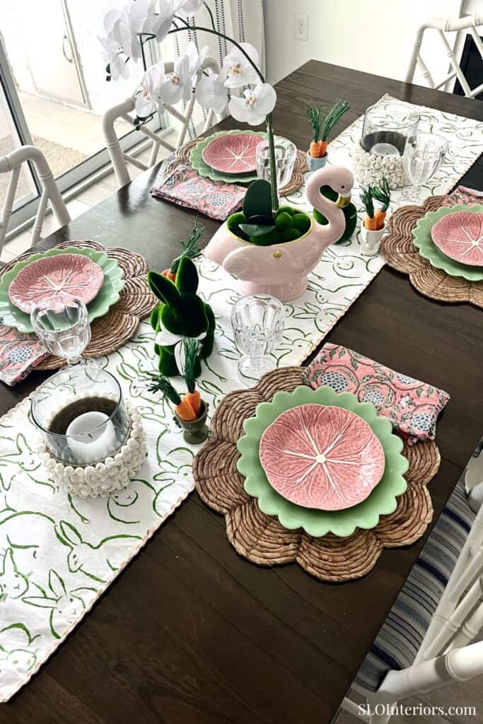 Elegant dining table setup with floral placemats, decorative swan centerpiece, and fresh flowers.