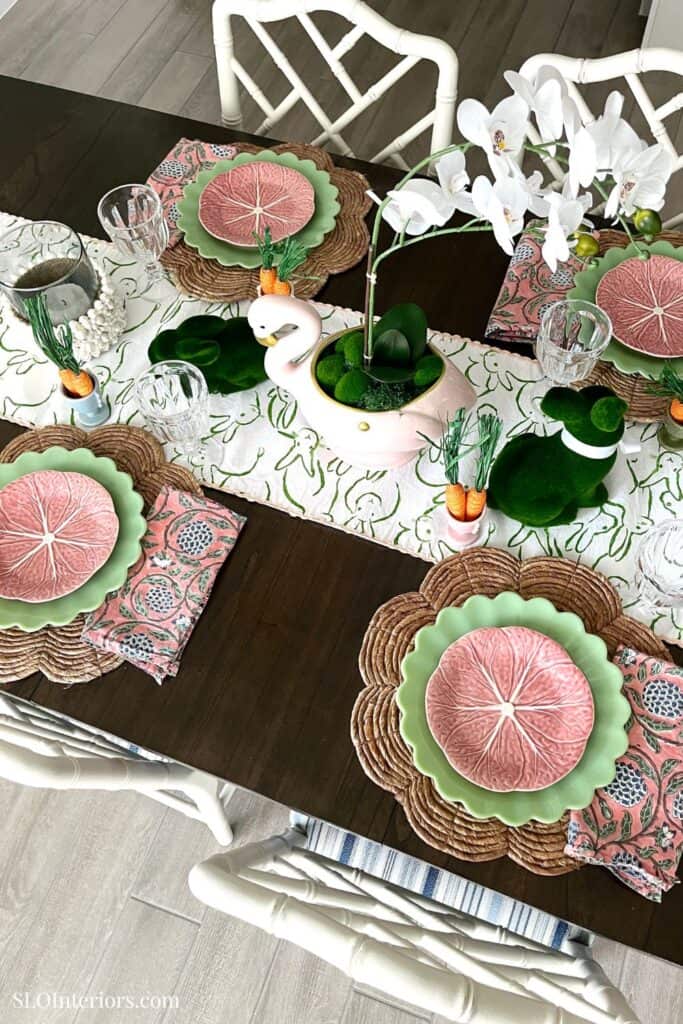 Elegant dining table setup with floral and fruit-themed tableware, white orchids centerpiece, and mo.