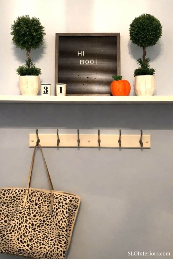 A cozy Halloween-themed home decor display with pumpkins, potted plants, and a welcome sign.