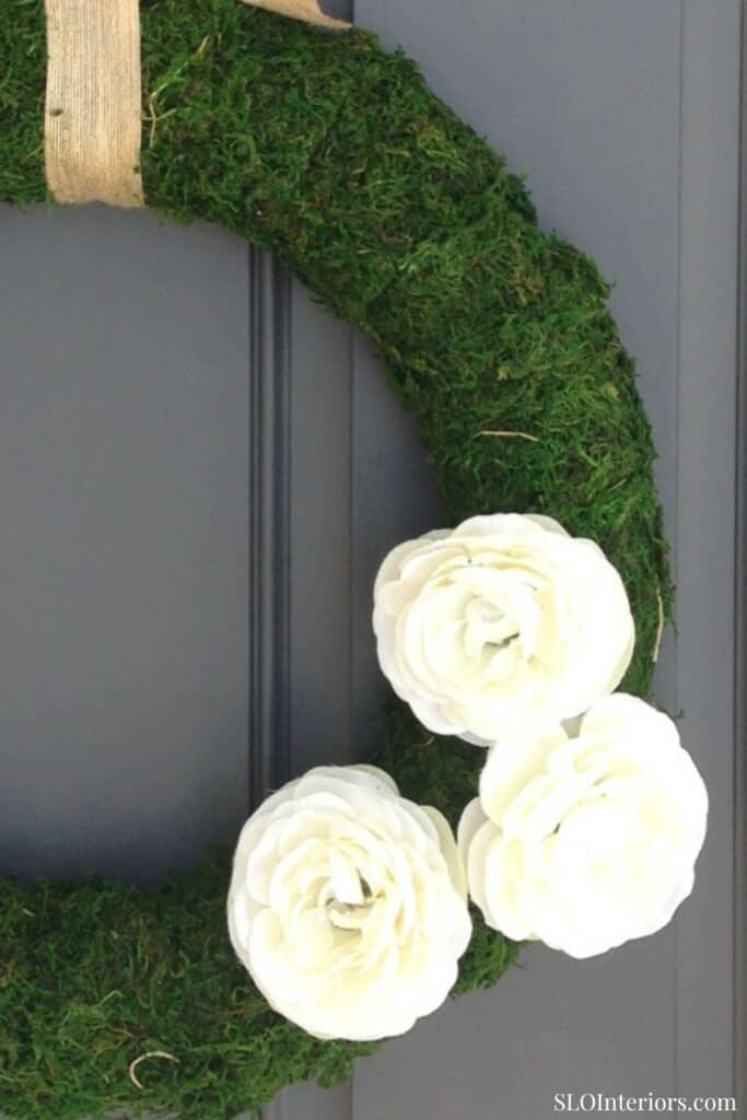 Close up of three white flowers on a moss wreath