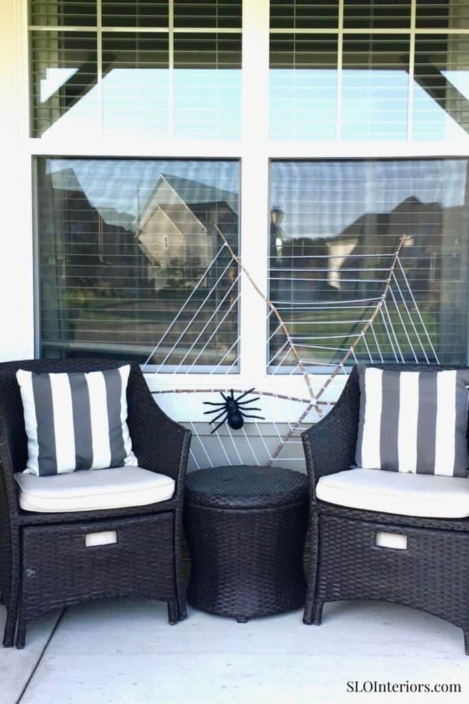 Cozy outdoor seating area with black wicker chairs and decorative spider decor.