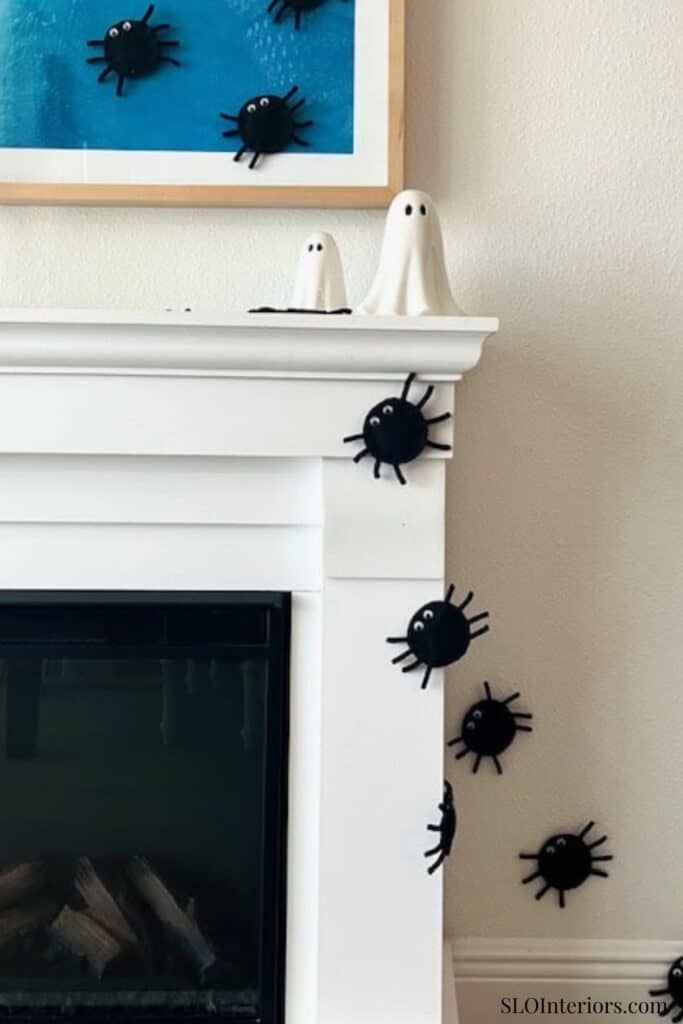 Cute black and white bug-themed decor on white fireplace mantel, modern interior design.