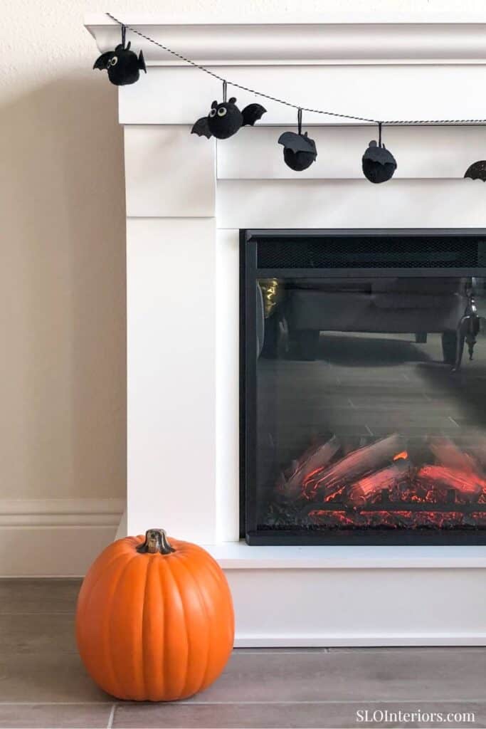 A cozy living room fireplace with Halloween decorations and a pumpkin, SLO Interiors.