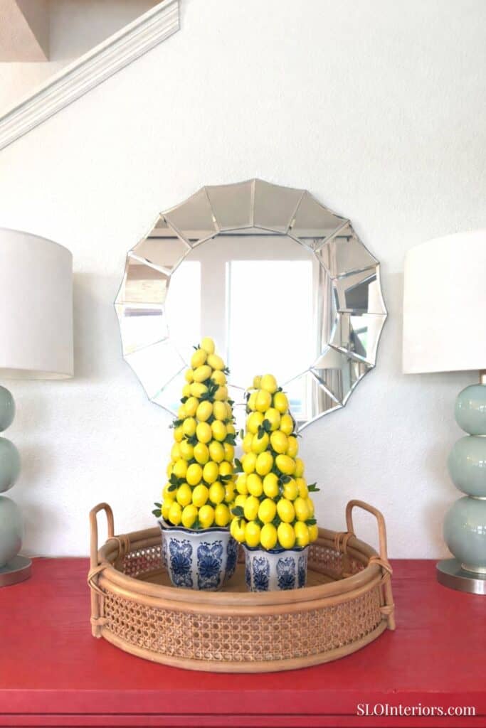 Lemon topiary decor with yellow lemons in blue and white pots, placed on a wicker tray in front of a.