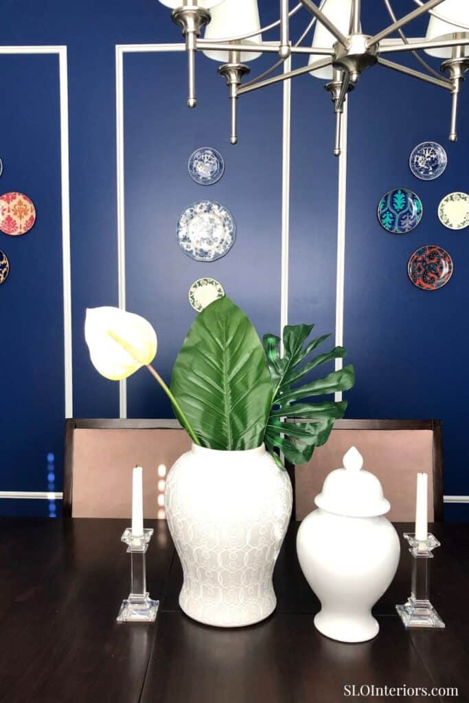 Elegant blue wall decor with vases and tropical leaves for stylish interior design.