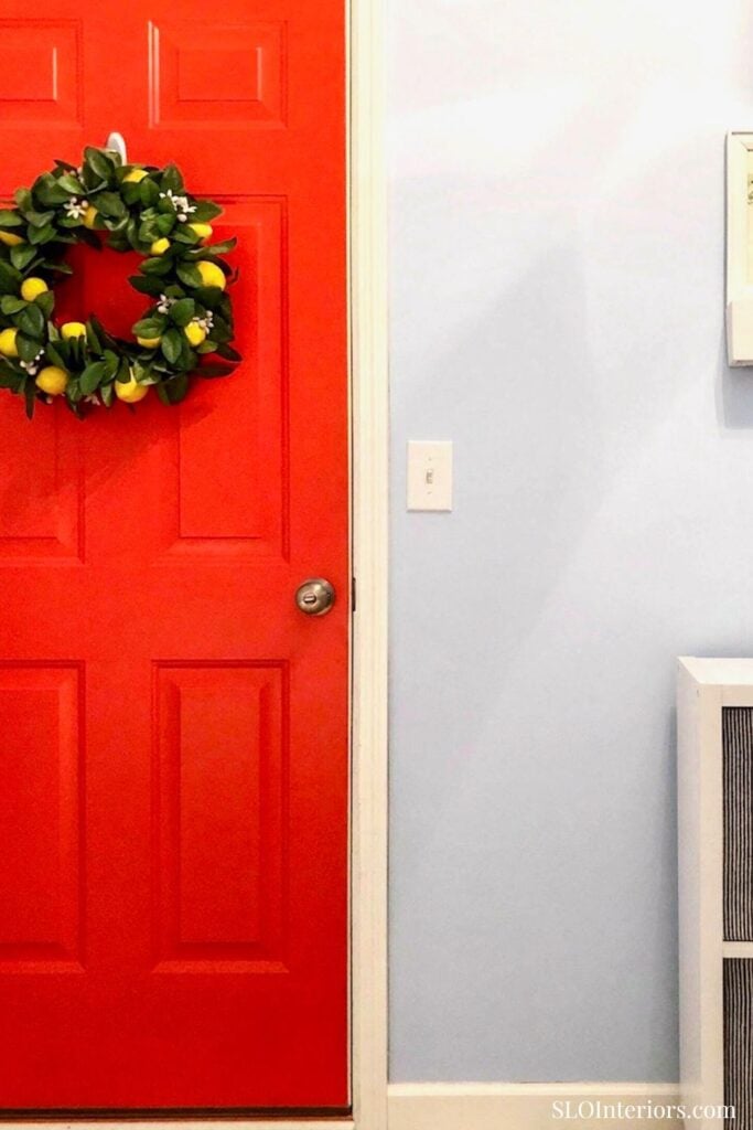 A colorful red door with a festive green wreath hanging on it.