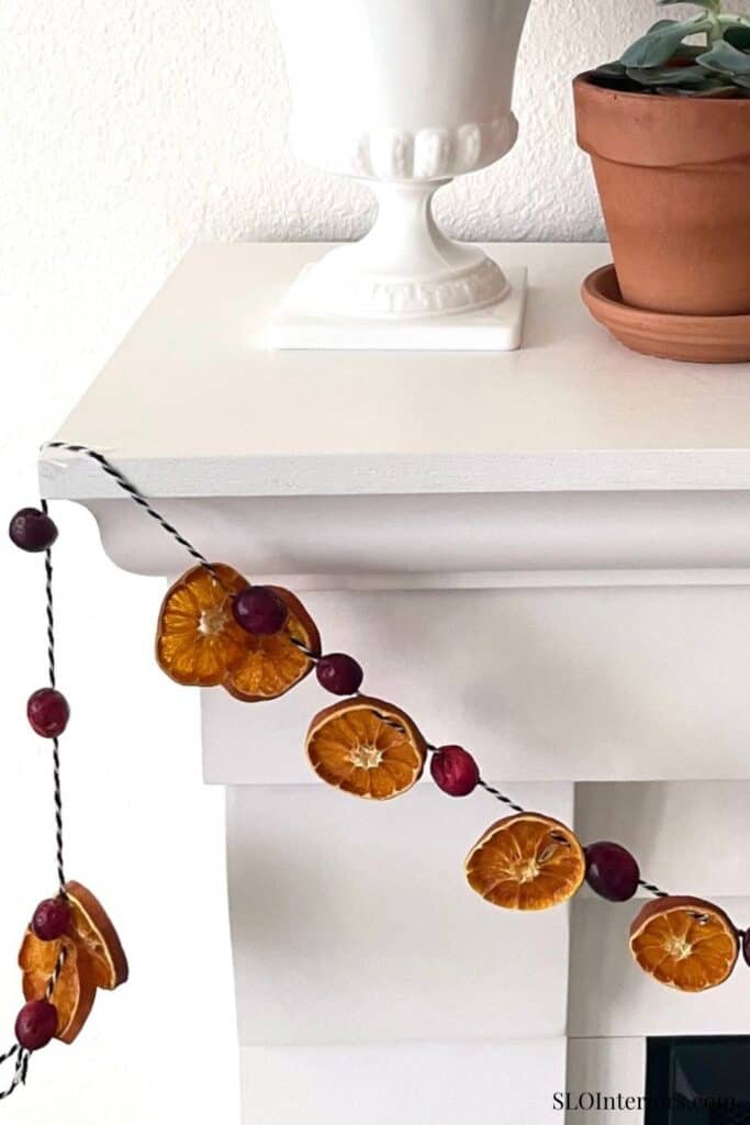 A cozy interior corner with a white table, potted plant, and decorative garland.