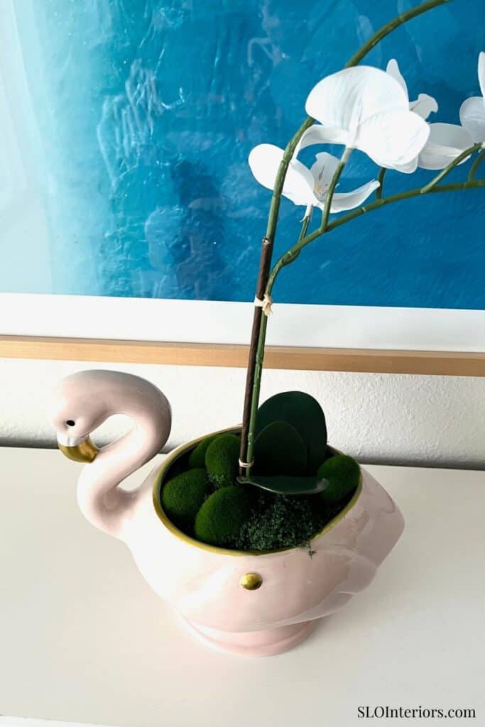 Elegant white orchid in a decorative swan-shaped planter with greenery, modern home decor.