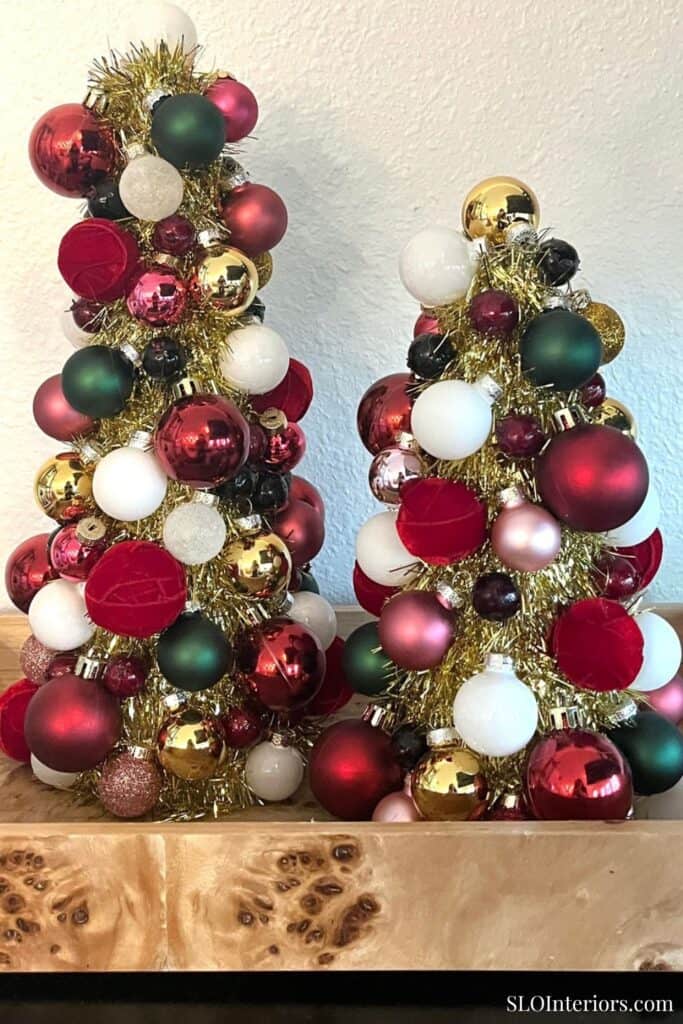 Red, white, green, and gold Christmas ornaments on small decorated trees for holiday decor.