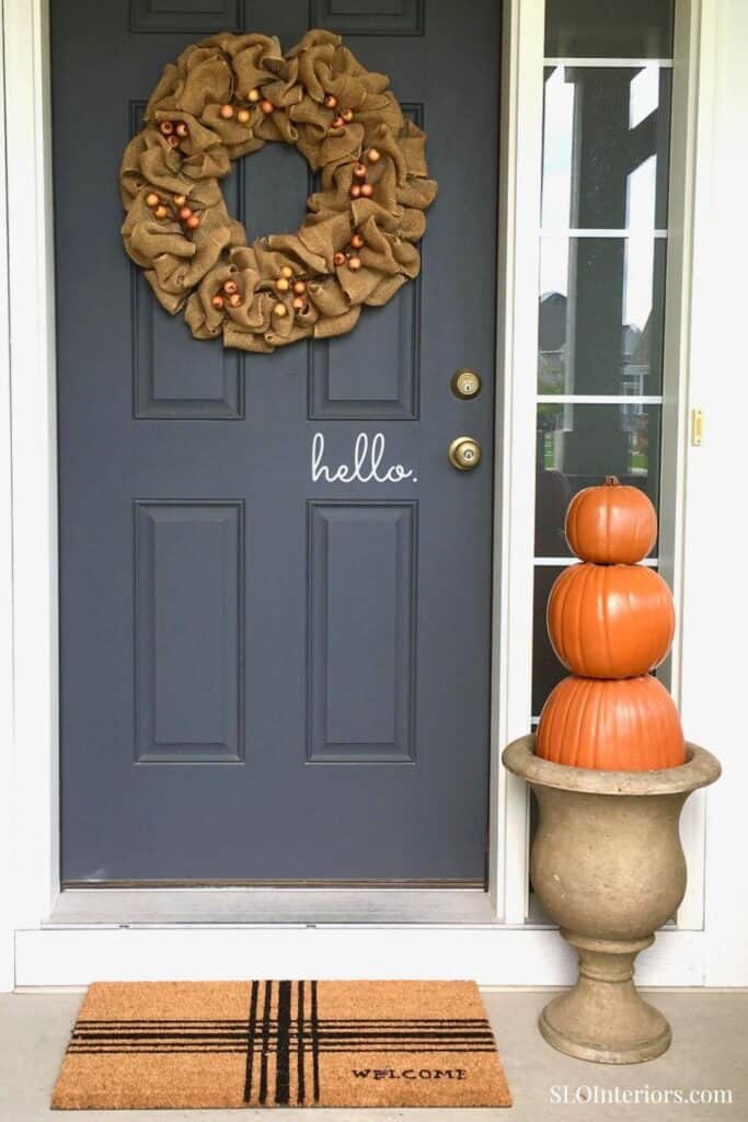 Front door decorated for fall with wreath and pumpkin display.