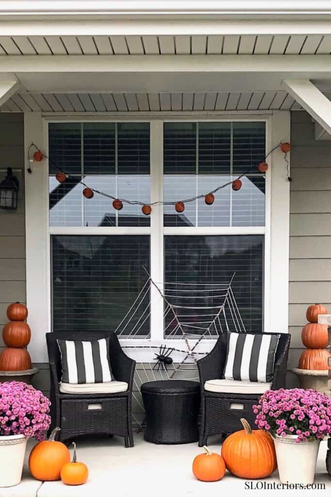 Cozy outdoor patio with black wicker chairs, pumpkins, and fall decorations.