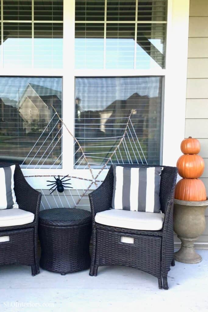 A cozy outdoor seating area with black wicker chairs, striped cushions, and decorative pumpkins.