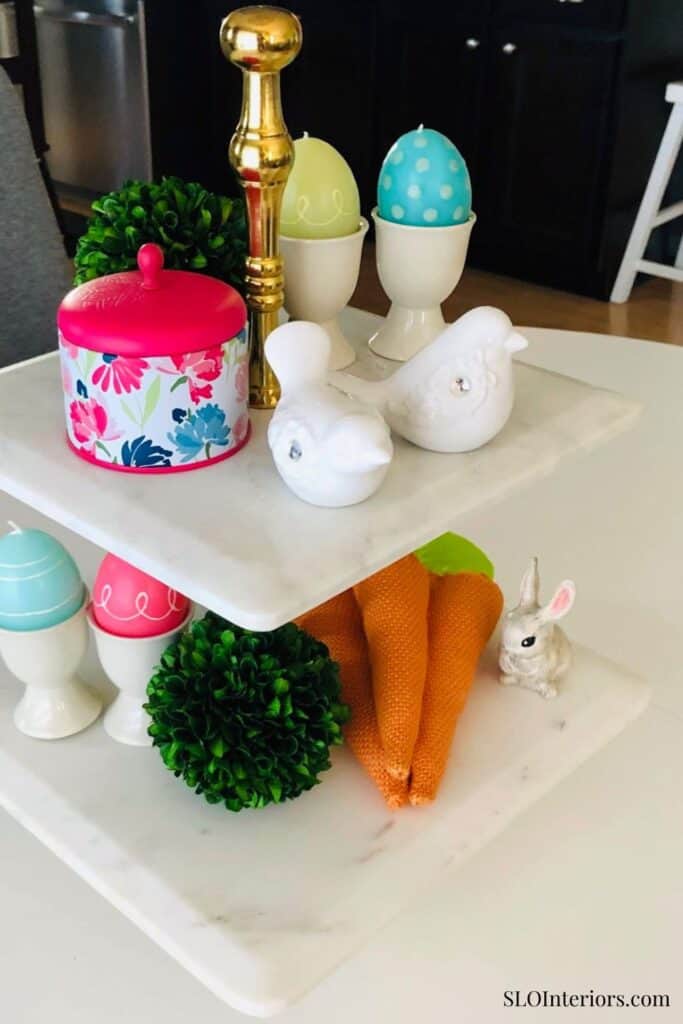 Bright Easter-themed table decor with colorful eggs, bunny figurines, and decorative plants.