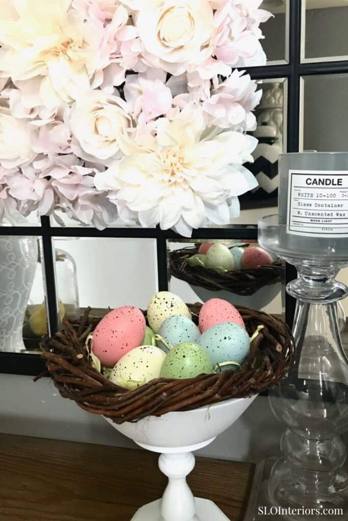 Elegant Easter eggs in a wicker basket with floral decor and candles at SLO Interiors.