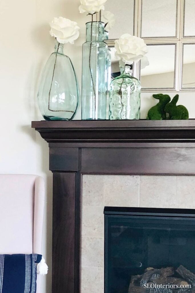 A modern fireplace mantel decorated with glass vases and white flowers for elegant interior design.