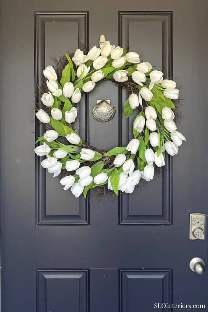 White tulip floral wreath hanging on a dark door, decorative home door wreath, SLO Interiors.