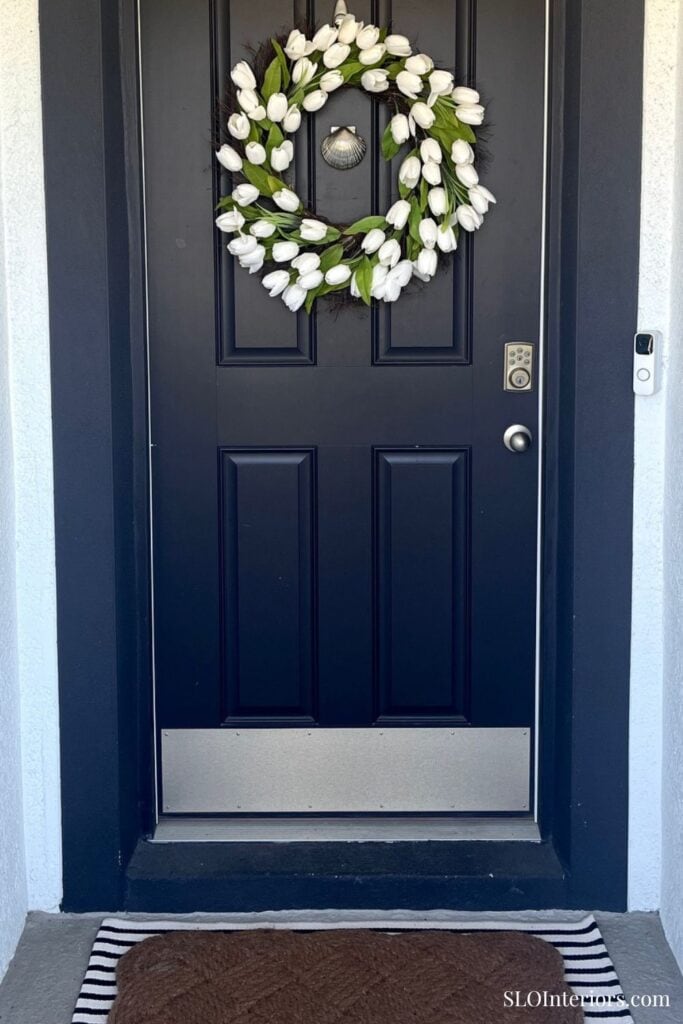 Elegant navy front door with white floral wreath, modern home entryway decor.