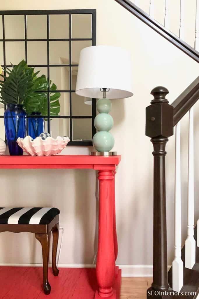 Modern entryway with colorful console table, decorative lamp, and stylish decor accents.