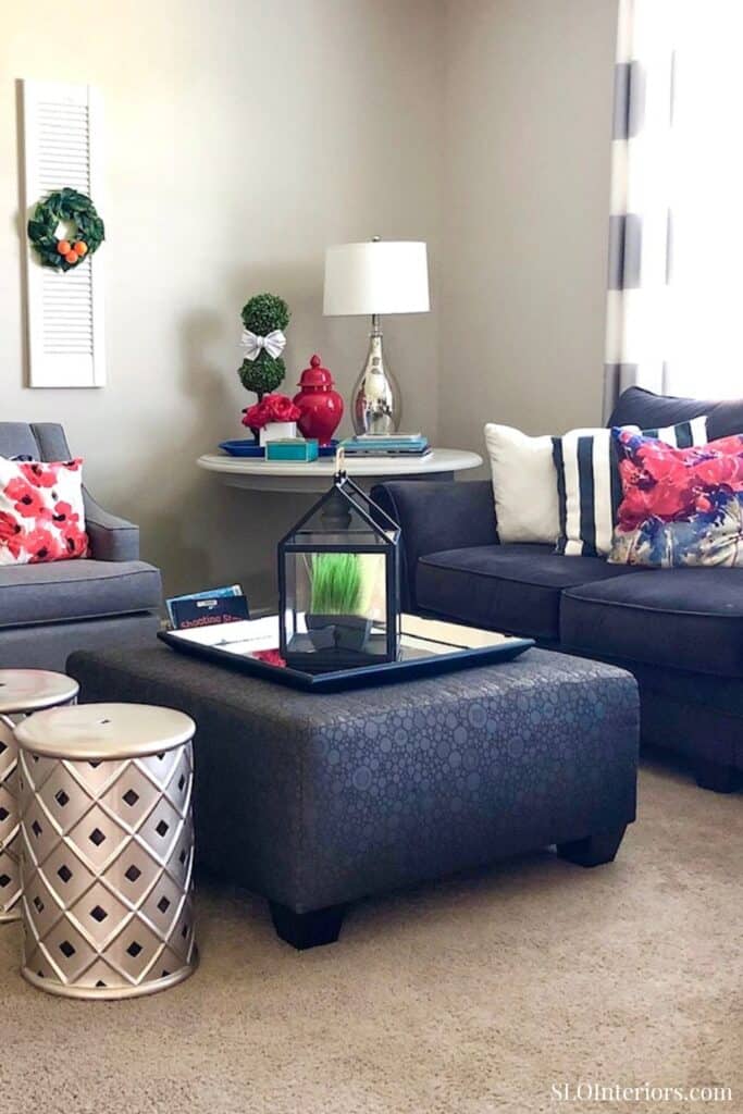 Modern living room with navy and gray sofas, colorful pillows, and decorative accents.