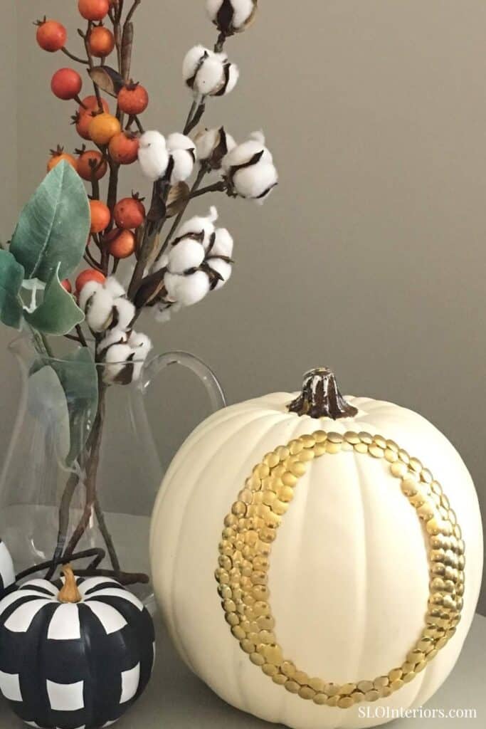 White pumpkin decorated with gold beads, cotton branches, and fall accents for seasonal decor.