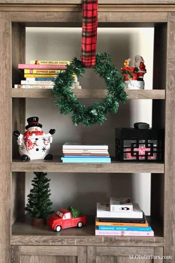 Festive holiday bookshelf with Christmas decorations and books at SLO Interiors.