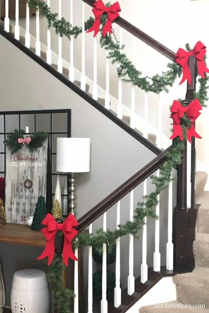 Festive Christmas staircase decor with garlands and red bows, holiday home interior.