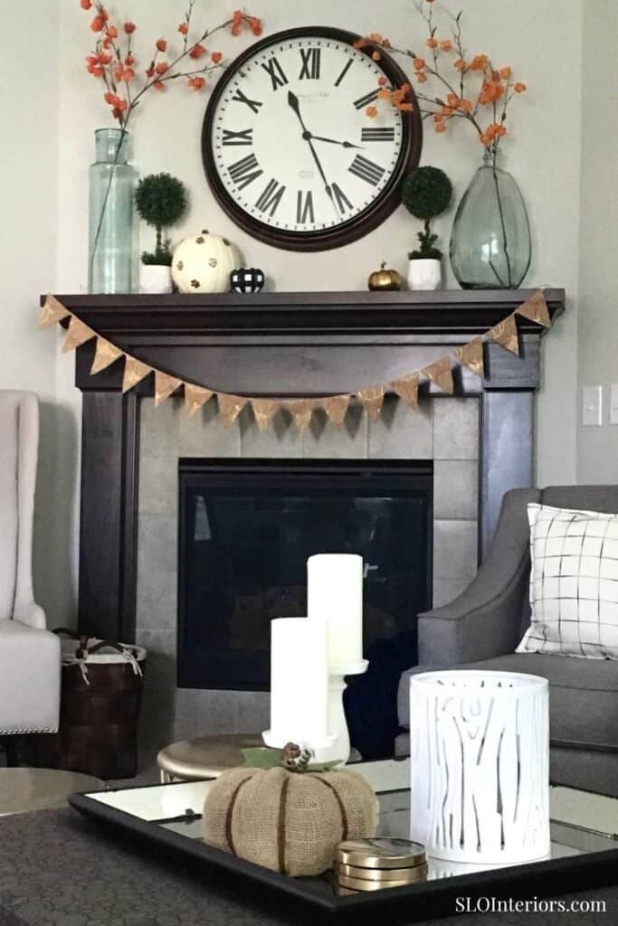Elegant living room fireplace mantel with decorative accents and wall clock, cozy interior design.