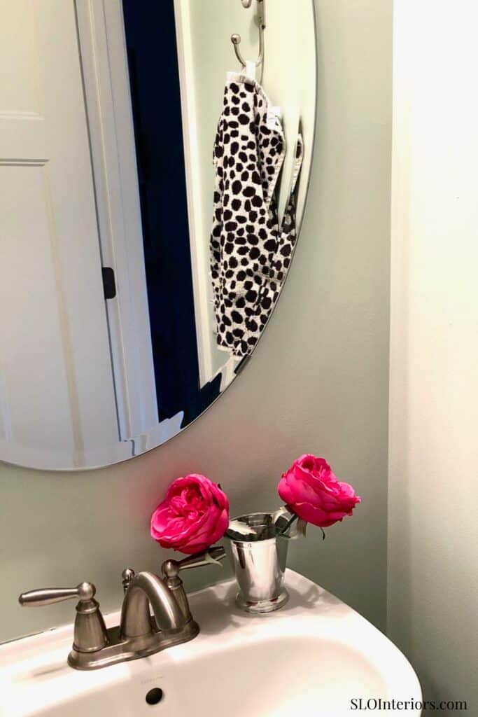 Elegant bathroom mirror with floral decor and stylish accessories, modern interior design.