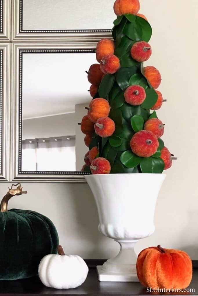 Bright autumn-themed floral arrangement with apples in a white vase, home decor.