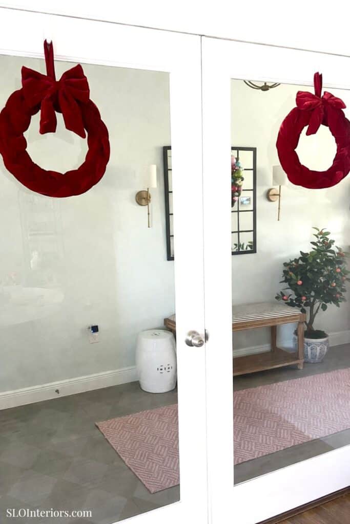 Red velvet Christmas wreaths hanging on glass door, holiday home decor, SLO Interiors.