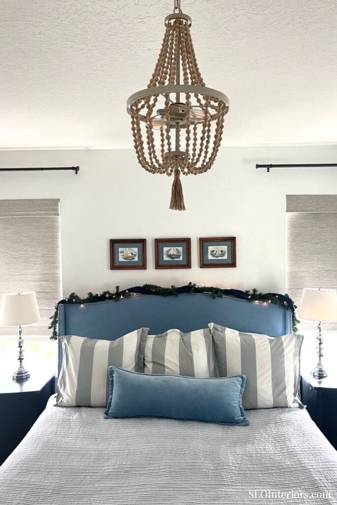 Elegant bedroom with blue and white decor, chandelier, and framed art, SLO Interiors.