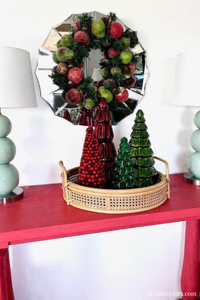 Festive holiday decor with Christmas trees and wreath on mirror wall in living room.