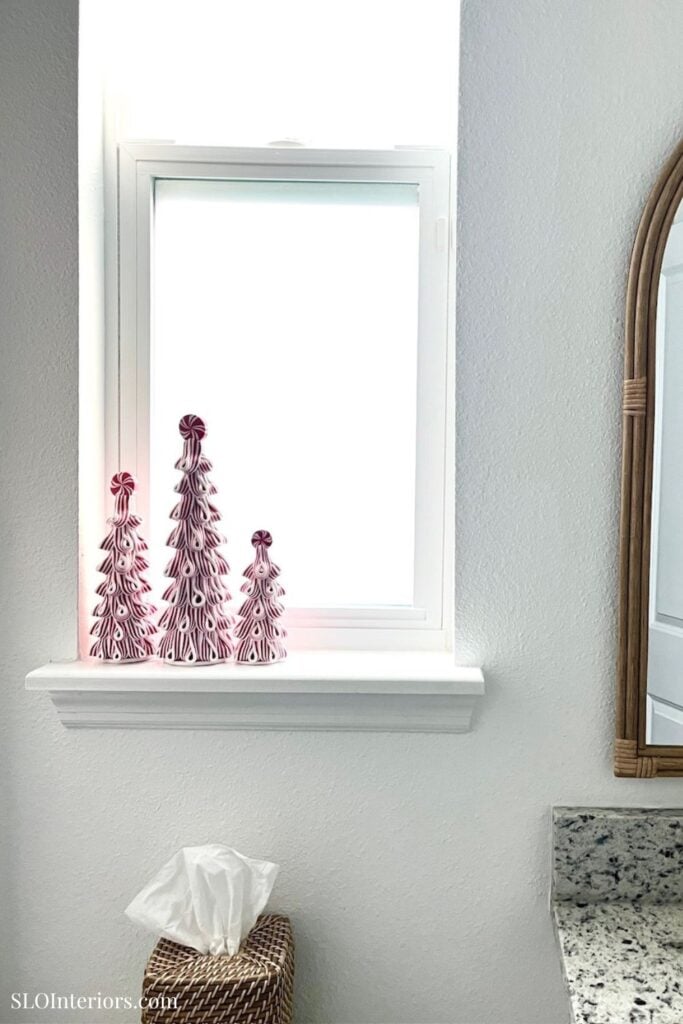 Elegant white window with pink decorative trees on the windowsill, modern interior design.