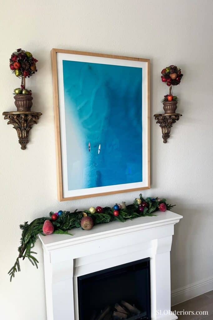 Elegant living room fireplace with holiday decorations and wall art, SLO Interiors.