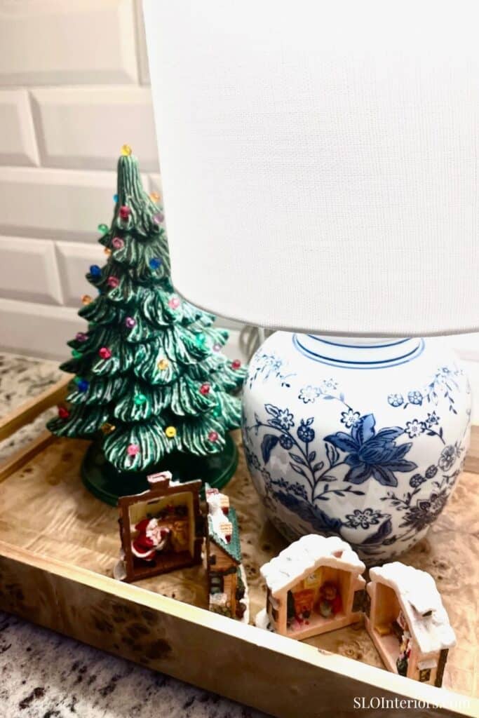 A Christmas tree, decorative lamp, and miniature nativity scene on a wooden tray.