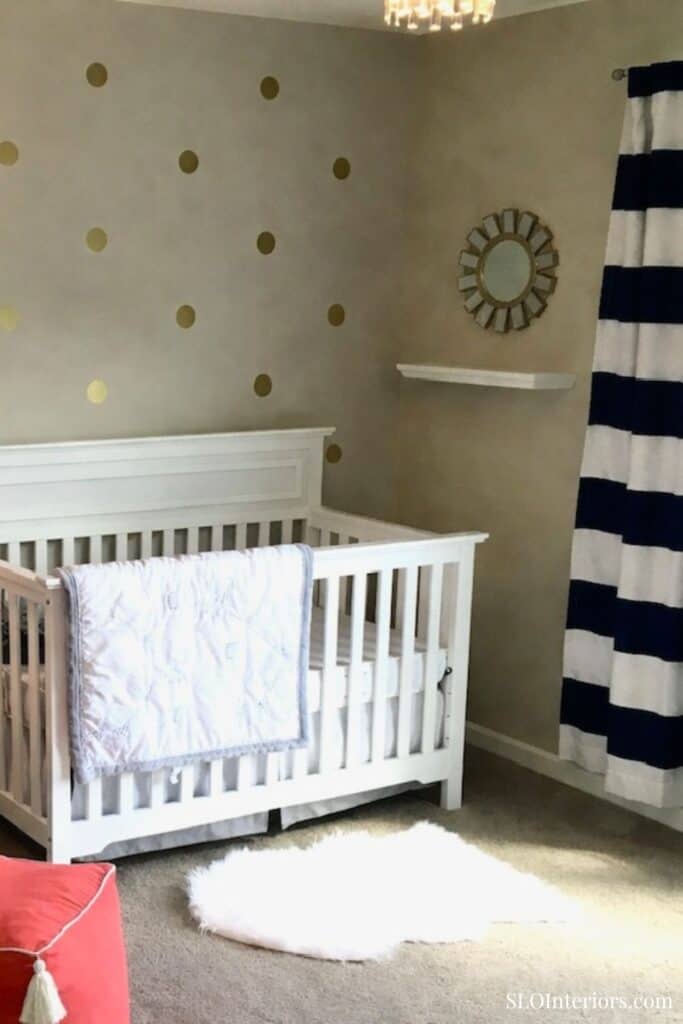 Modern nursery with white crib, gold polka dot wall, and navy striped curtains for stylish interior.