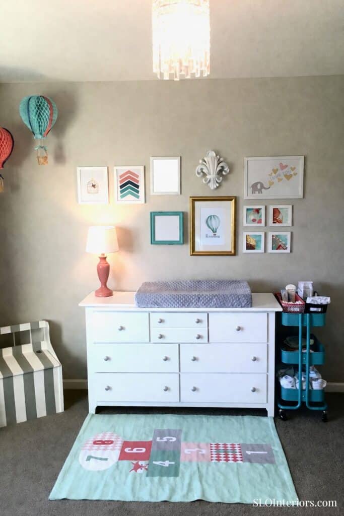 A colorful nursery changing station with wall art and storage options.