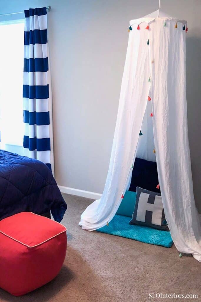 A colorful indoor play tent with hanging lights and cozy cushions in a child's bedroom.