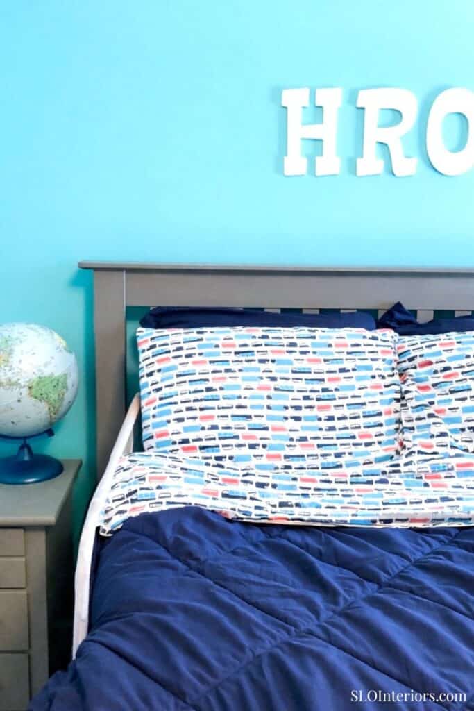 A cozy bedroom with colorful bedding and a globe on the nightstand.