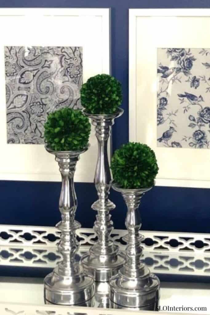 Elegant silver candle holders with green topiary plants, stylish home decor accents.