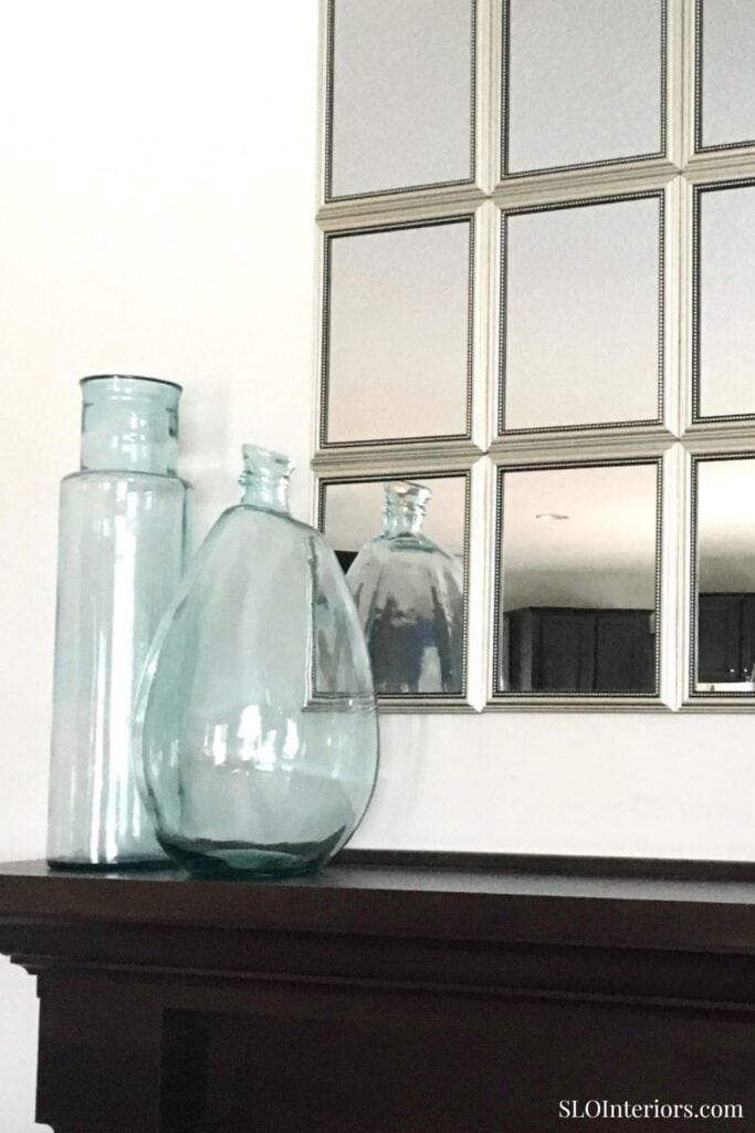 Elegant glass vases and decorative mirror wall art in modern interior design.