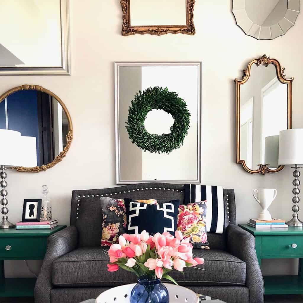 A cozy living room with floral pillows, mirrors, and a wreath decor.